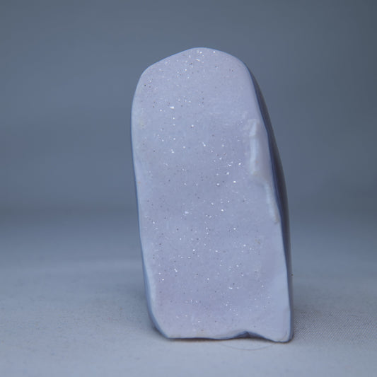 Close view of tiny druzy crystals across the broad icy-blue face and polished dark edge alternate view