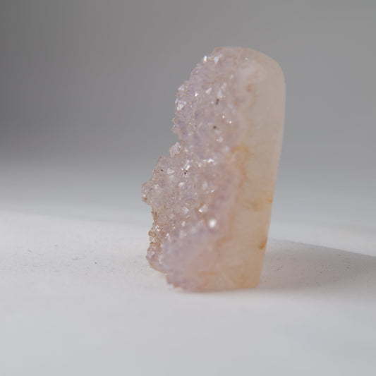 Side view of the druzy, with a sparkling ridge along the left edge and a smooth pale reverse. alternate view