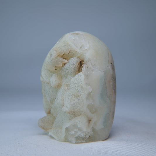 Upright view of the pale geode showing fine sparkling crystals across its uneven front. alternate view