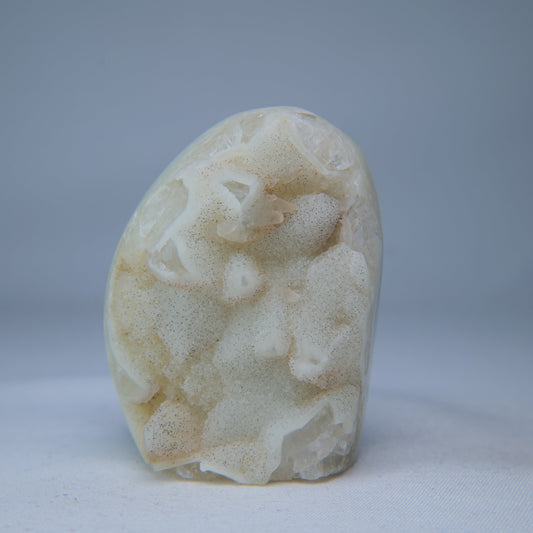 Front view of the cream-white druzy geode, with a rounded outline and crystal-lined face.