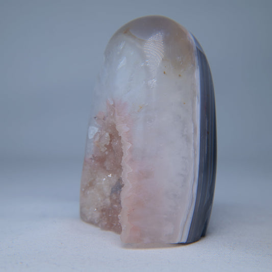 Angled view of the pink crystal opening beside a polished blue-grey agate side. alternate view