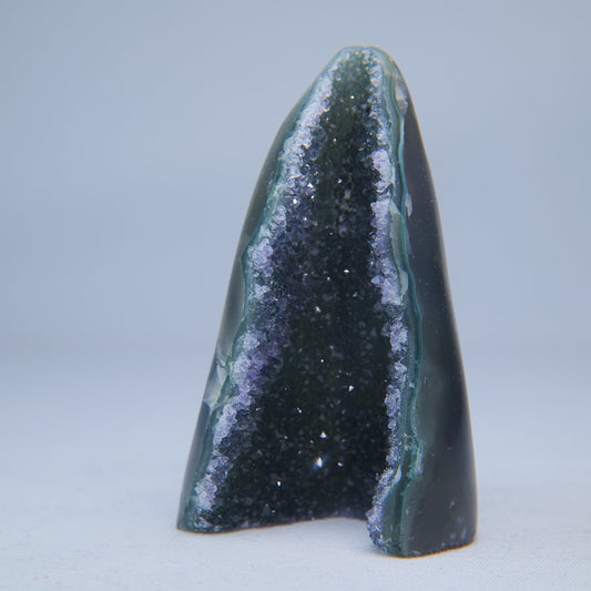 Blue-green agate geode showing a narrow, crystal-lined dark opening between polished sides. alternate view