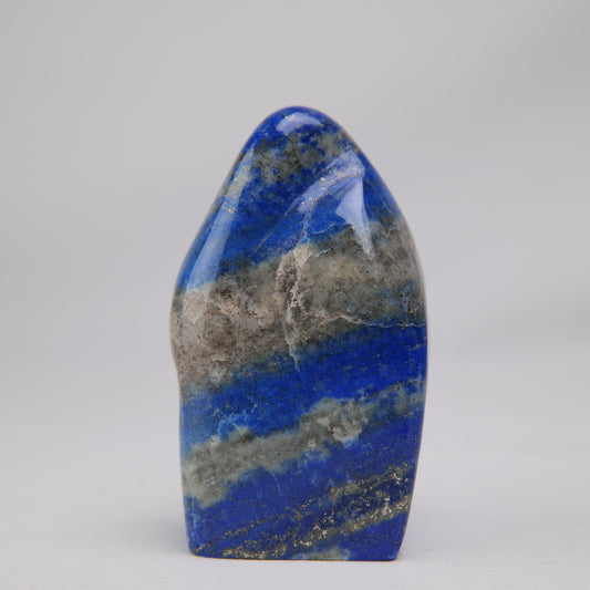 Lapis lazuli freeform, upright face with a broad pale calcite band across vivid blue.