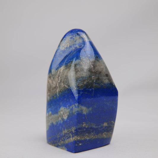 Angled lapis lazuli face showing mottled grey calcite and fine gold pyrite flecks. alternate view