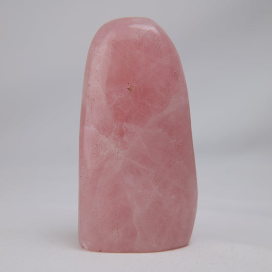 Rose quartz freeform, broad blush-pink face with faint cloudy veils and a small brown inclusion near the upper centre.