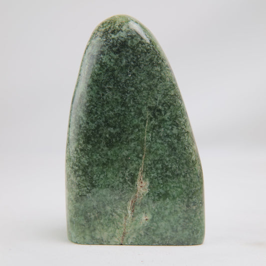 Broad face of the 416 g Serpentine freeform, deep green with a fine pale vein descending toward the flat base.
